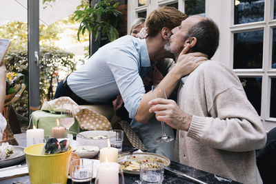 Parent kissing son during party in restaurant