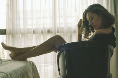 Side view of woman sitting on chair at home