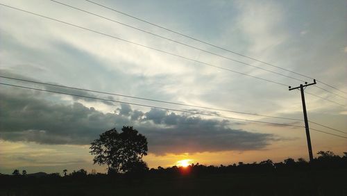 Low angle view of silhouette electricity pylon on field against sky