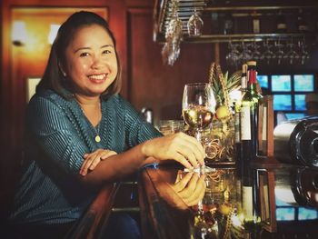 Portrait of a smiling young woman with drink in restaurant