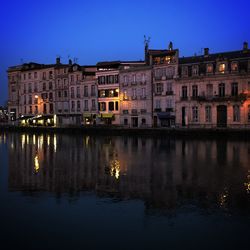 Reflection of buildings in lake against sky at night