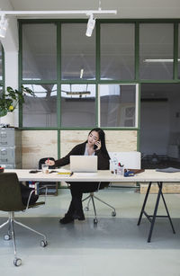 Woman using smart phone at desk in creative office