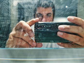 Portrait of man photographing through mobile phone