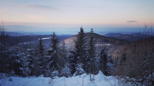 Snow covered landscape against sky during sunset