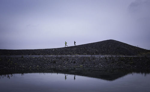 Man standing by lake against sky