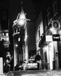 Illuminated street amidst buildings in city at night