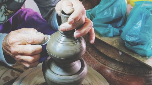 Midsection of potter polishing earthenware on pottery wheel