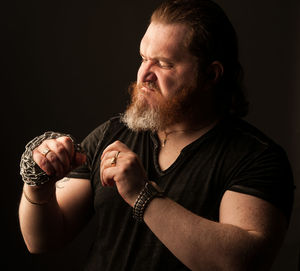 Portrait of man holding camera over black background