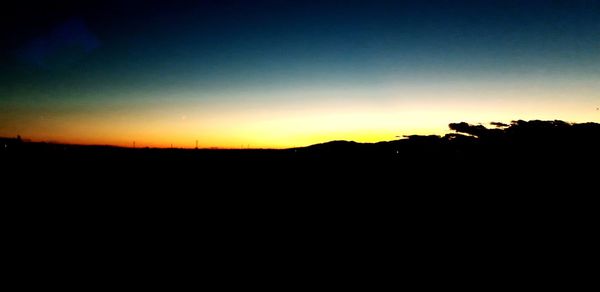 Silhouette landscape against clear sky at sunset