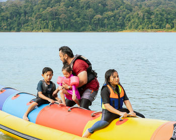 Rear view of friends on boat against sea