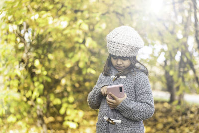 Portrait of man holding mobile phone in park