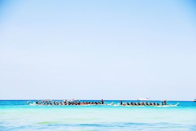 People on beach against clear sky