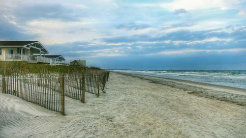 Scenic view of beach against cloudy sky