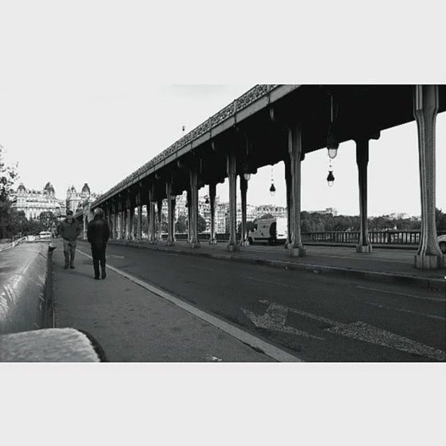 transportation, architecture, built structure, walking, men, clear sky, road, lifestyles, rear view, the way forward, person, full length, street, travel, connection, bridge - man made structure, city, leisure activity