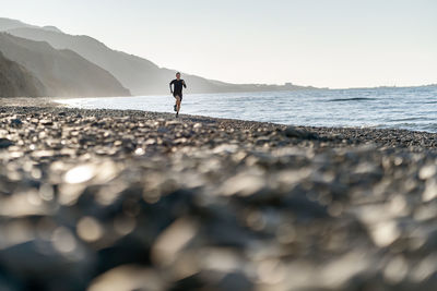 Full length of man standing at beach against sky