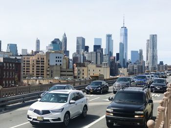 Cars on road amidst buildings in city against clear sky