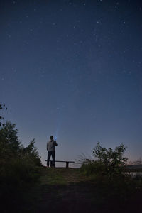 Rear view of man standing on land against sky at night