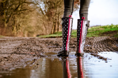 Low section of woman walking on dirt road