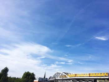 Low angle view of bridge and buildings against blue sky