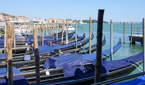 Boats moored in canal against blue sky