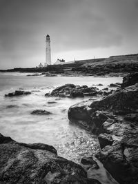 Lighthouse by sea against sky