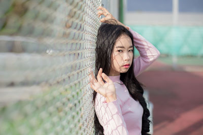 Side view portrait of young woman standing by net at court