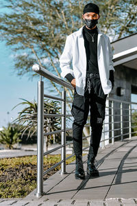 Portrait of young man standing against railing