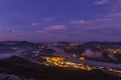 Illuminated cityscape against sky at dusk