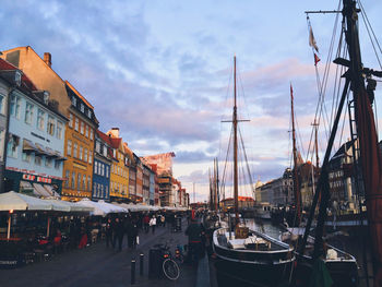 Boats moored at harbor by buildings in city against sky