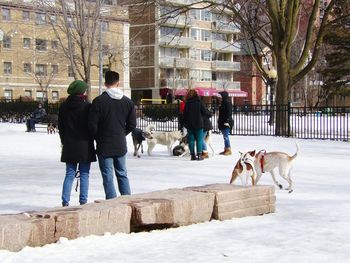 Rear view of people walking on snow covered city in winter