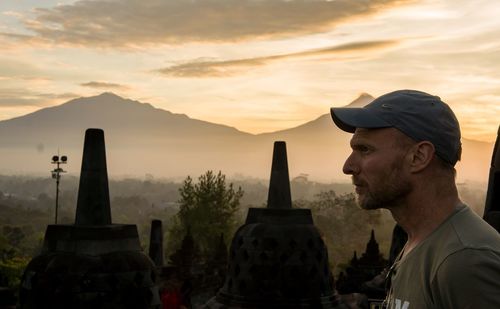 Profile view of man with historic temples in background against sky