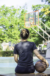 Rear view of woman with basketball sitting on table