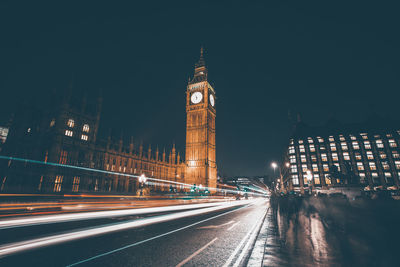 Light trails on road amidst buildings at night