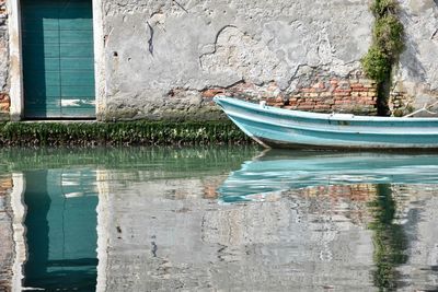 Boat moored in lake against wall