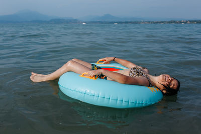 Happy girl with short dark hair relaxing lying down on top of the inflatable ring