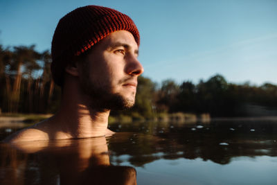 Young man in hat bathing in the ice water alone at the morning