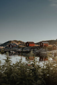 Houses by lake and buildings against clear sky