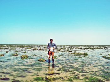 Full length of man standing on beach against clear sky