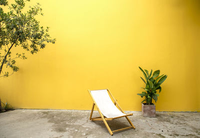 Empty chairs and table against yellow wall