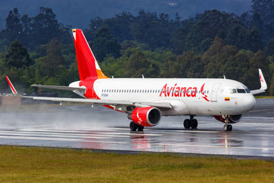 Red airplane on airport runway against mountains