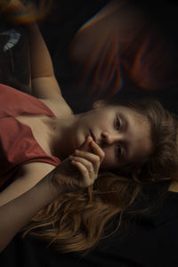 Portrait of young woman lying on bed at home