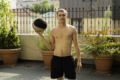 Portrait of shirtless man standing against wall