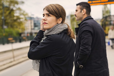 Side view of female and male passengers waiting for tram at platform