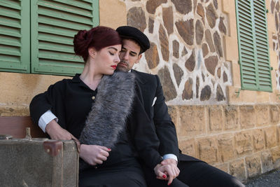 Affectionate couple sitting by house