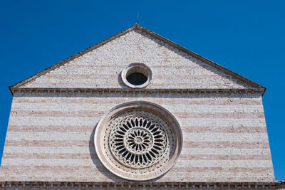 Low angle view of cross on building against clear blue sky