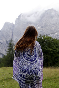 Rear view of woman standing on field against mountain