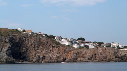 Buildings by sea against sky