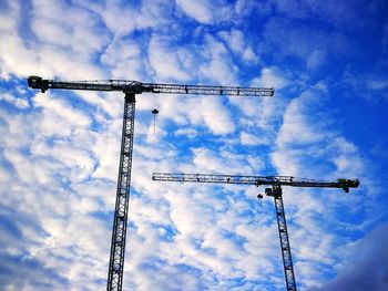 Low angle view of cranes against blue sky