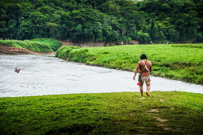 Rear view of man walking on riverbank