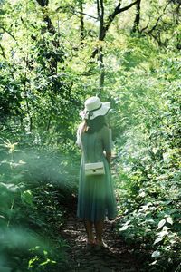 Woman standing by tree in forest